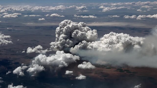 Flight along a massive forest fire in a wooded mountain region, with huge masses of smoke rising into the atmosphere and forming billowing clouds - 4k aerial video footage