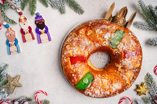Roscon de reyes with cream and christmas ornaments on a white background, top view. Roscon is a traditional Spanish Christmas pastry cake with decoration. Kings day concept spanish three kings cake.