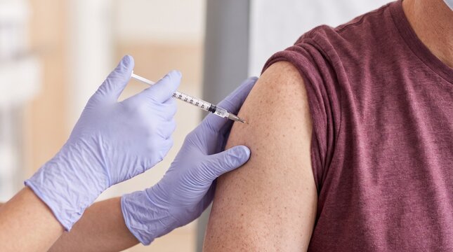 Preventive Medicine: Healthcare worker administers vaccine injection into adult upper arm