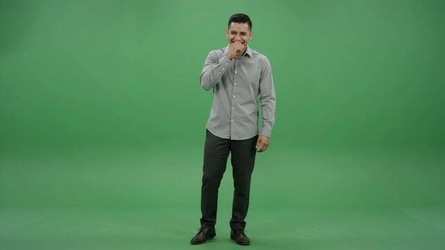 A happy man in a grey shirt and dark pants laughing on a green screen background.