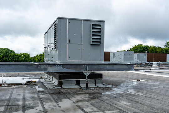 Industrial, commercial HVAC equipment on steel dunnage, and pipes on gray roof.