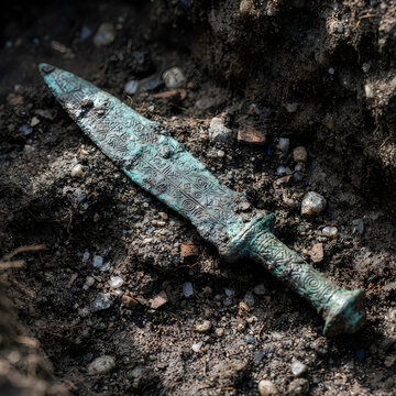 Ancient verdigris bronze dagger unearthed during archaeological dig with archaeology artifact excavation discovery metalwork verdigris treasure heritage
