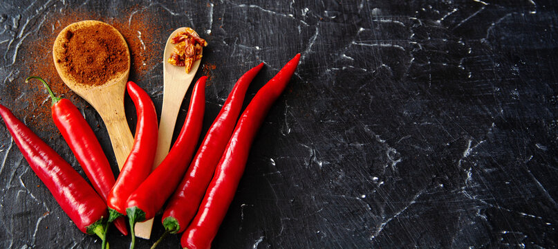 Vibrant red chili peppers on rustic wooden board with spices and garlic	