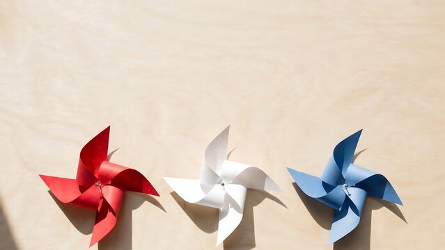 Three colorful pinwheel toys in red white and blue standing in a row against a plain background