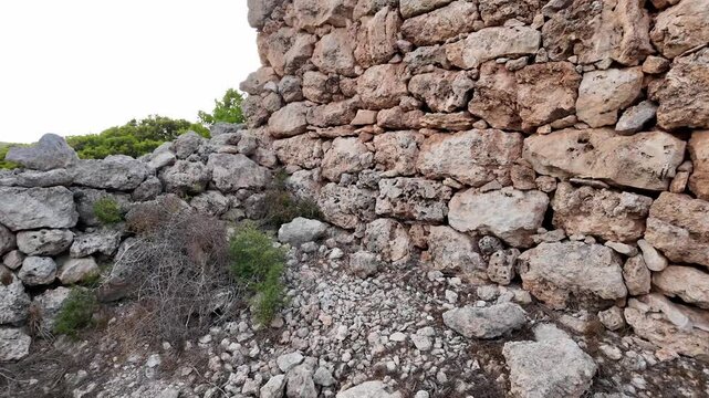 Ancient stone walls stand weathered and strong. Approaching and revealing iron ring used to tie anymals
