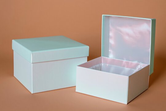 Pair of matte mint and white product boxes shown open and closed against a warm amber background for premium gift packaging and branding mockups