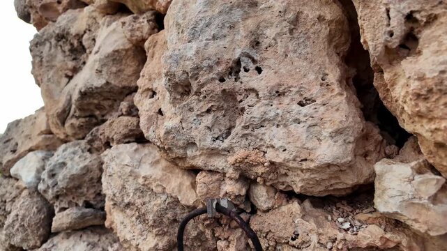Ancient stone walls stand weathered and strong. Approaching and revealing iron ring used to tie anymals