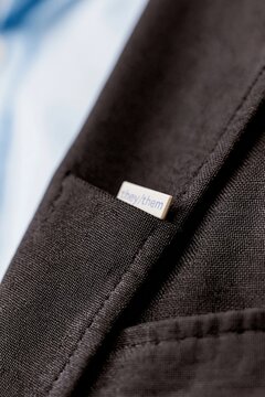 Personal pronoun pin with they them text on a charcoal suit jacket, showcasing a matte texture and woven fabric for corporate inclusivity themes