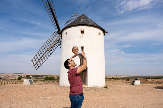 Father holding baby up by traditional Windmill in Tembleque