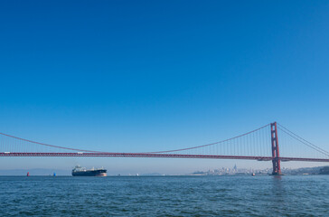 Obraz premium The iconic Golden Gate Bridge, a suspension bridge, spans the strait with San Francisco skyline in the background.