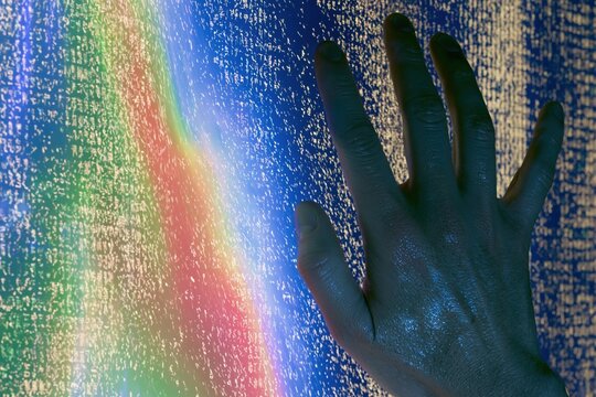 A human hand touching a glowing stream of digital data on a screen, featuring vivid neon light and fine skin texture for futuristic technology and connectivity concepts