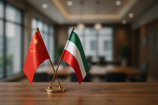 Crossed miniature flags of china and kuwait on a wooden table in a blurred conference room with soft ambient lighting and dark furniture