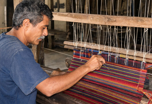 Skilled artisan weaver working on a traditional wooden handloom to create colorful fabric textile