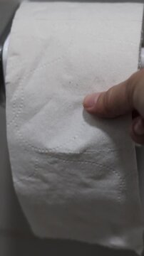 Una mano de mujer adulta agarrando papel higi&eacute;nico movi&eacute;ndolo o agarrando para realizar su limpieza cotidiana en el ba&ntilde;o. Estilo de vida. Video vertical     
