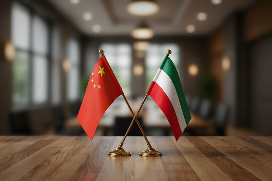 Miniature flags of china and kuwait crossed on a wooden table in a blurred conference room with soft ambient lighting and dark interior