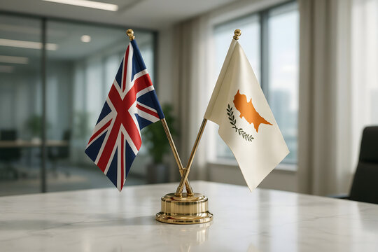 Miniature flags of the united kingdom and cyprus on a golden stand placed on a white marble desk in a modern corporate office meeting space
