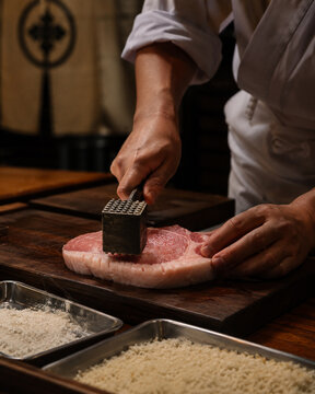 Close Up of Chef Scoring and Pounding Pork Cutlet on Wooden Board for Authentic Tonkatsu Preparation.