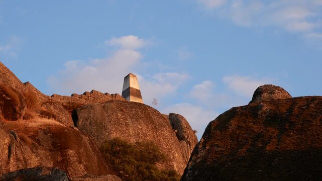 Triangulation pillar overlooking Monsanto, Portugal, with panoramic views across mountains and valleys. Historic high point surrounded by granite rocks and dramatic landscapes.