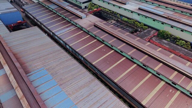 Aerial push in of old industrial corrugated metal warehouse roofs with geometric rust texture and parallel lines, offering a minimalist wabi-sabi atmosphere and copy space for industry backgrounds.