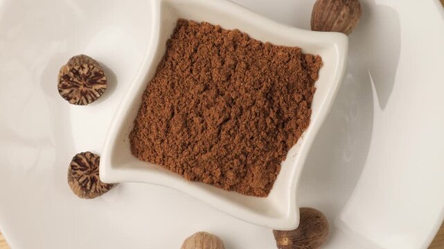 Aromatic nutmeg powder and whole seeds rotating