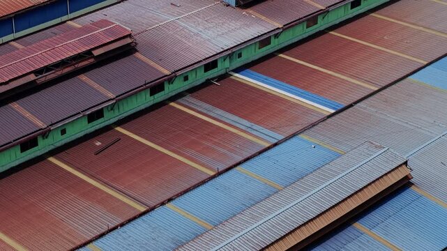 Aerial view of industrial corrugated metal roof with geometric patterns and heavy rust texture. Abstract weathered architectural background with slow push in movement.