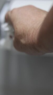 Una mano de mujer adulta tomando el  papel higi&eacute;nico movi&eacute;ndolo o agarr&aacute;ndolo  para realizar su limpieza cotidiana en el ba&ntilde;o. Estilo de vida. Video vertical     