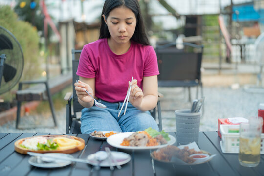 Young woman eating a meal outdoors at a casual restaurant with various dishes