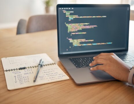 Hands type on laptop with colorful code displayed