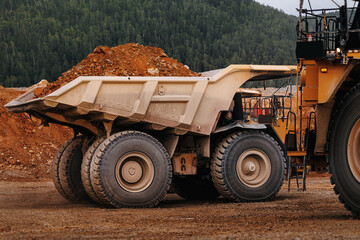 Heavy duty mining dump truck side view loaded with earth at quarry site for industrial background © Parilov
