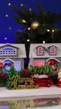 A yellow car quickly drives past a decorated Christmas village and an unusual Santa Claus darts past