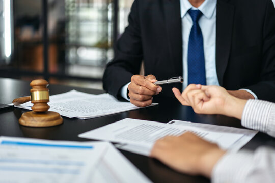 A man in a suit is handing a pen to a woman