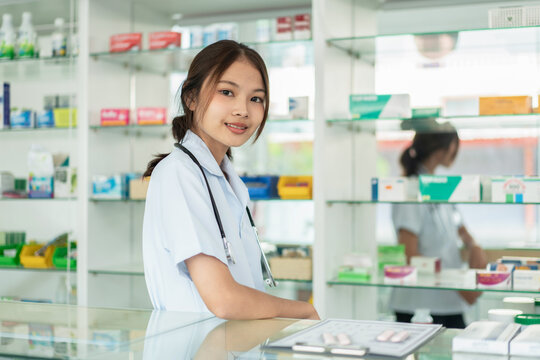 A woman in a white uniform stands behind a counter in a pharmacy