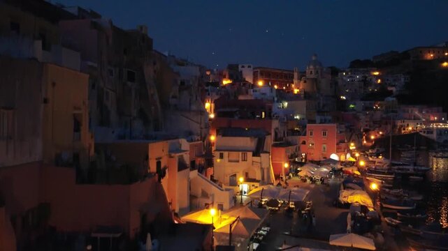 Aerial nightscape of Procida coastline and illuminated
