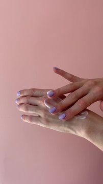 Close up of female hands applying moisturizing hand cream, lotion skincare routine, beauty self care concept, skincare product, cosmetic treatment on nude beige background. Moisturizer application