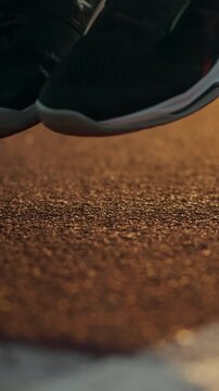 A focused athlete in training gear jumps rope at dawn on an outdoor sports facility, the routine emphasizing conditioning and coordination as the early light illuminates the track and equipment