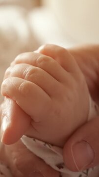 Close up view of a newborn baby's tiny hand gently wrapped around an adult's finger, symbolizing the profound bond of love, trust, protection, and connection within a family