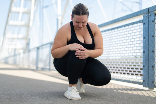 Plus size woman feeling knee pain during outdoor workout