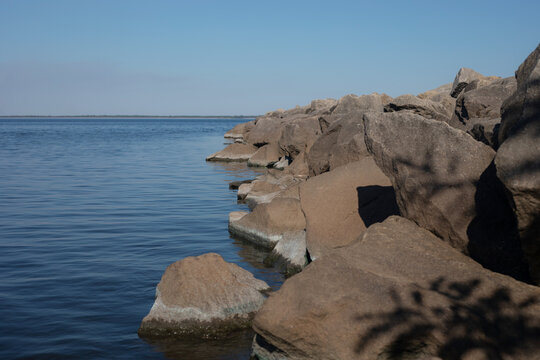 Large shoreline rocks beside peaceful blue sea