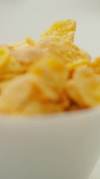 A stream of cereal pours into a clean white bowl on a table, with a separate bowl of fresh blueberries sitting nearby, part of a morning breakfast setup with healthy food options today