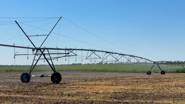 Center pivot irrigation system watering a field of crops on a sunny day