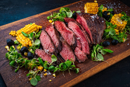 BBQ roasted under-blade steak chuck roast, denver cut beef steak with grilled vegetables, maiz corn, green salad served as close-up on a wooden board