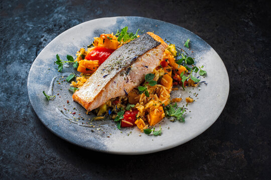 Fried salmon fish fillet with pumpkin and sweet potato rosti gratin served as close-up on a design plate