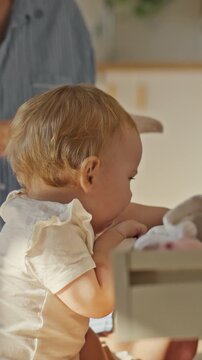 In a family living room, a mother and child fold laundry together while a housewife sorts items into closets, all engaged in routine cleaning of the household under natural light, concept