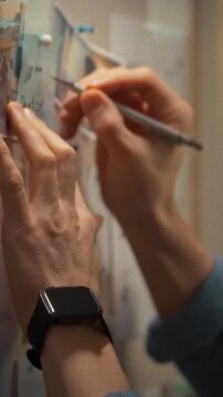 In a quiet office at night, an office worker stands before a wall covered in colorful sticky notes, brainstorming tasks while using a pen to highlight key details in search of solutions, concept