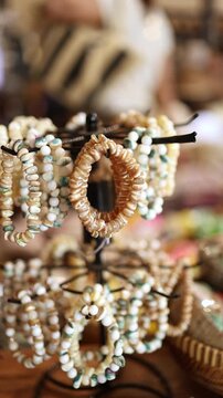 Handmade seashell and wooden bead bracelets displayed on a rotating stand in a gift shop in Nha Trang, Vietnam. Local souvenir jewelry and accessories at street market counter, travel concept.