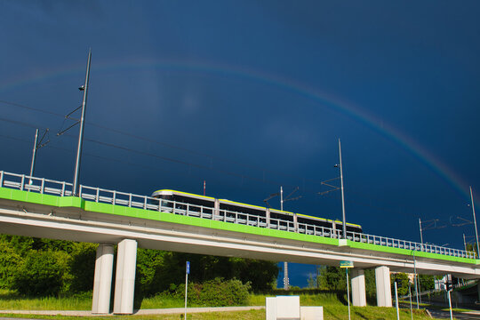 Panoramiczny widok jadącego estakadą tramwaju z tęczą w tle