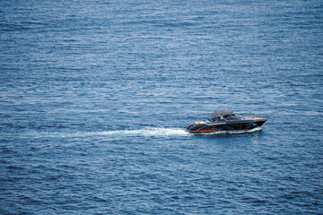 Fototapeta premium Motorboat cruising across the Mediterranean Sea near Magaluf, Mallorca, Balearic Islands, Spain, leaving a white wake on open blue water in a minimalist coastal scene.