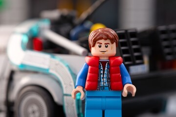 Fototapeta premium Tambov, Russian Federation - July 30, 2026 Portrait of a Lego Marty McFly minifigure standing near DeLorean time machine car from Back to the Future.