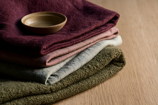 Stacked olive sage and amethyst textiles on pale oak