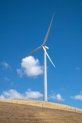 Fototapeta premium Tall Wind Turbine Stands Against a Clear Blue Sky, Capturing Renewable Energy on a Sunny Day